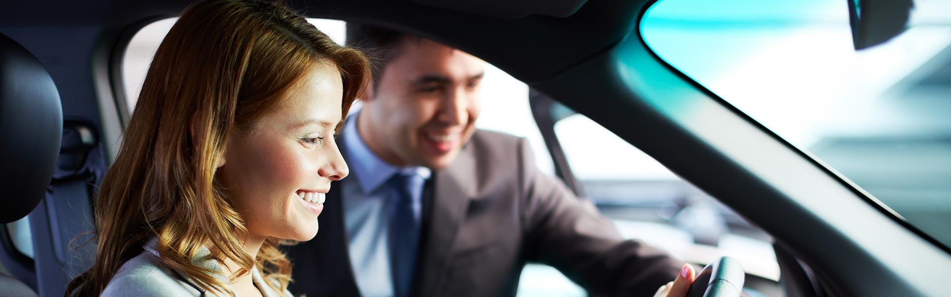 Woman sitting in car being shown details by salesman